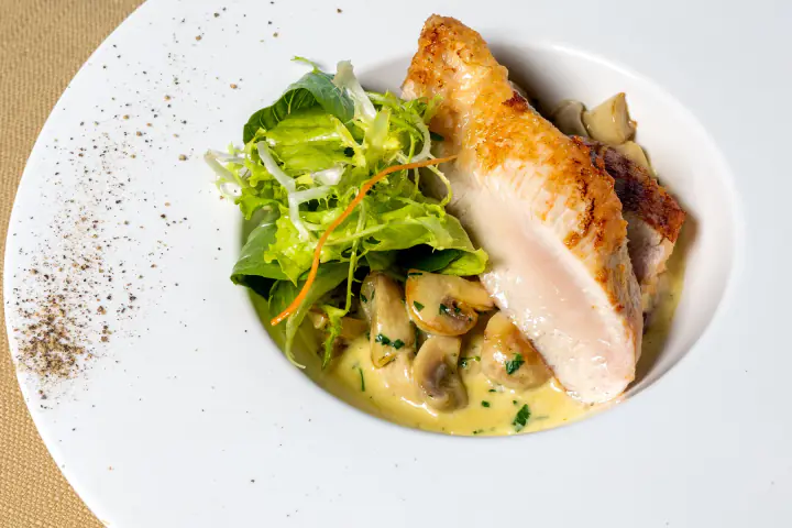 Roasted chicken breast served over creamy mushrooms with fresh greens