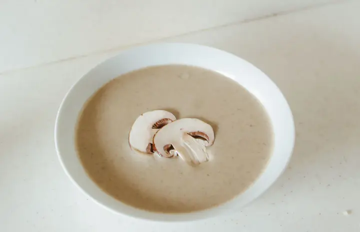 Creamy mushroom soup topped with fresh mushroom slices